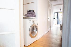a laundry room with a washer and dryer at Modern flat with KING bed, garden & outdoor dining in London