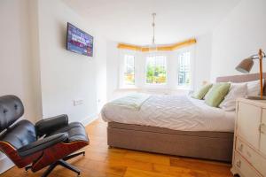 1 dormitorio con cama, silla y ventana en Modern flat with KING bed, garden & outdoor dining en Londres