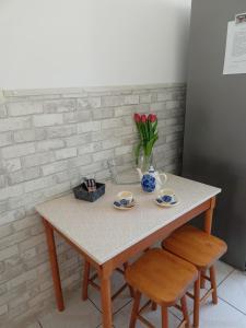 a table with two cups and a vase of flowers at Apartament Mazury in Olecko