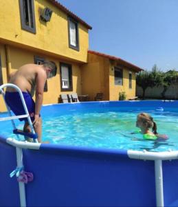 een man en een klein meisje in een zwembad bij BertoaLand Relax y Diversión Apartamento de 2 dormitorios dobles con terraza privada y zona de juegos compartida in Carballo