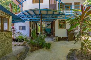 a house with a blue roof and some plants at Uvita River Guesthouse in Uvita