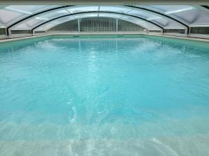 uma grande piscina de água azul num edifício em la ferme de tonton Jules 2 em Entraigues-sur-la-Sorgue