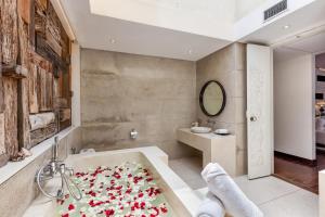 a bathroom with a bath tub filled with red flowers at The Chand's Boutique Villa Batu Belig in Seminyak