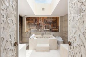 a bathroom with a tub and a toilet at The Chand's Boutique Villa Batu Belig in Seminyak