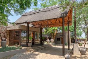 a pavilion with a thatched roof in a park at Zebula Boutique Hotel in Mabula