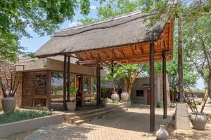 einen Pavillon mit einem Strohdach in einem Park in der Unterkunft Zebula Boutique Hotel in Mabula