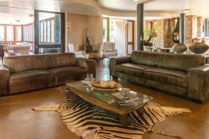 a living room with leather furniture and a zebra rug at Zebula Boutique Hotel in Mabula