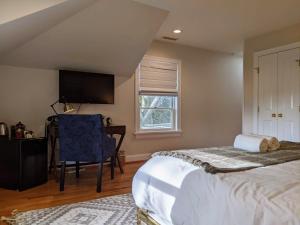 a bedroom with a bed and a chair and a television at Stanton House Inn in Greenwich