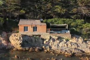 a small house on a rocky island in the water at Au plus près de l'eau in Coti-Chiavari