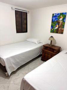 two beds in a room with a table and a window at Acogedor apartamento cerca al centro de Medellin in Medellín