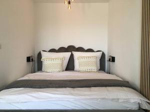 um quarto com uma cama grande com lençóis brancos e almofadas em Gemütliches Apartment mit wundervollem Weitblick em Löffingen