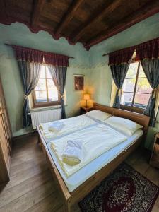 a bedroom with a large bed and two windows at Apartments Belopeški Dvori in Kranjska Gora