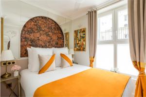 una camera da letto con un grande letto con una coperta arancione di Luxury 3 Bedroom & 3 Bathroom Apartment - Louvre a Parigi