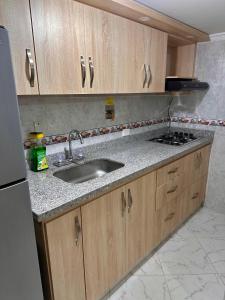 a kitchen with a sink and wooden cabinets at Acogedor apartamento cerca al centro de Medellin in Medellín