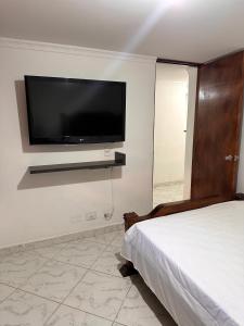 a bedroom with a bed and a flat screen tv on the wall at Acogedor apartamento cerca al centro de Medellin in Medellín