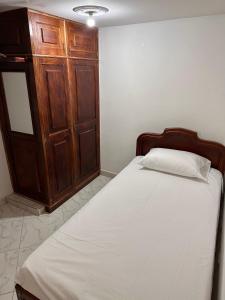 a bedroom with a bed and a wooden cabinet at Acogedor apartamento cerca al centro de Medellin in Medellín