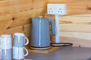una taza de café azul en un estante junto a un interruptor de luz en The Woolpack Glamping en Maidstone