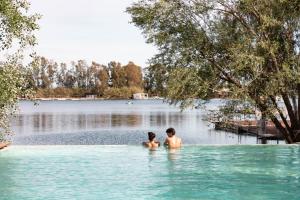 un hombre y una mujer de pie en el agua en un lago en Nabi Resort Glamping & SPA en Castel Volturno