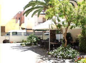 a restaurant with a table and chairs and a palm tree at Hotel Alguer in Alghero