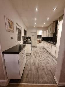 a large kitchen with white cabinets and a wooden floor at Lovely home close to MCR centre inc Cinema in Manchester