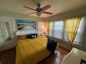 a bedroom with a yellow bed with a ceiling fan at PAG Beachhouse Rentals in St. Pete Beach