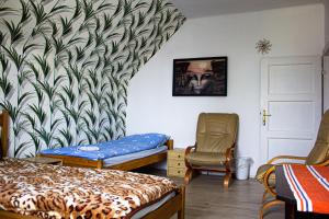 チェシンにあるDomek na Wzgórzuのベッド2台、椅子、絵画が備わる客室です。