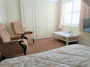 スランディドノにあるGranby Houseのベッドルーム1室(ベッド1台、椅子2脚、テーブル付)
