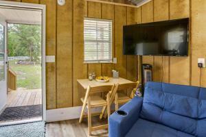 Habitación pequeña con mesa, TV y sofá azul. en Pet-Friendly Gulf Coast Rental Near Keaton Beach!, en Perry