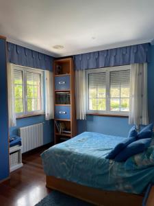 1 dormitorio con 1 cama con paredes y ventanas azules en Cabo de Veiga, en Trabada