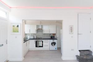 a kitchen with white cabinets and a washer and dryer at Monroe House Leeds in Leeds