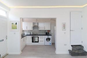 a kitchen with white cabinets and a washer and dryer at Monroe House Leeds in Leeds