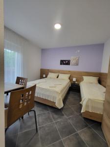 2 camas en una habitación con mesa y sillas en Vila Pčelica Petra en Soko Banja