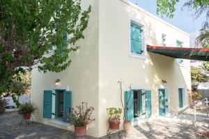 a white house with blue shutters and potted plants at Kos Gaia Garden House 