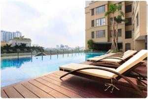 a row of lounge chairs on a deck next to a swimming pool at January Apartment in Ho Chi Minh City