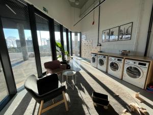 pralnia z wieloma pralkami i krzesłami w obiekcie Apartament Manhattan Premium - I-wsza Dzielnica - by Kairos Apartments w mieście Katowice