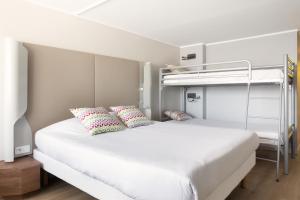 a bedroom with a white bed with two bunk beds at Campanile Dole in Dole