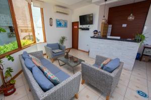 een woonkamer met een bank en stoelen en een bar bij Blue Marlin Hotel in Puerto Baquerizo Moreno