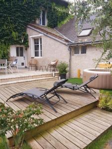 eine Terrasse mit 2 Liegestühlen und einer Badewanne in der Unterkunft Gite de charme au bord de l'Indre avec jacuzzi in Monts