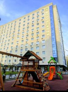 ein Hotel mit einem Spielplatz vor einem Gebäude in der Unterkunft Апартаменты в центре, в новом доме in Almaty