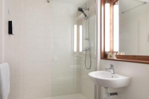 a white bathroom with a sink and a shower at Campanile Dole in Dole