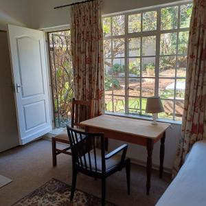 um quarto com uma secretária, uma janela e uma cama em Craighall Park Stylish Garden Studio em Joanesburgo
