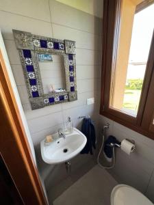 een badkamer met een wastafel, een spiegel en een toilet bij Suite familiare immersa nel verde in Bagnário Arsa