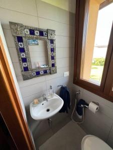 a bathroom with a sink and a mirror and a toilet at Suite familiare immersa nel verde in Bagnário Arsa