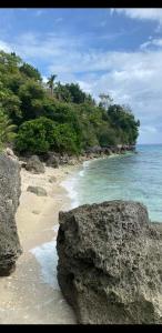 a beach with rocks and the ocean and trees at Sandra's Holiday House in Oslob