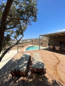 a wooden deck with a bench and a swimming pool at Villa Prasini in Agios Sostis