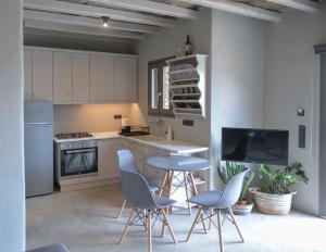 a kitchen with white cabinets and a table and chairs at Villa Prasini in Agios Sostis