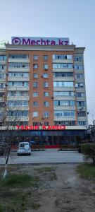 duży budynek z samochodem zaparkowanym przed nim w obiekcie Апартаменты в центре города w mieście Aktobe