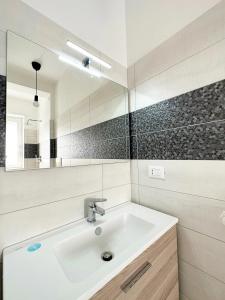 ein weißes Badezimmer mit einem Waschbecken und einem Spiegel in der Unterkunft Cuore e Sole - Attico Monolocale con Parcheggio Privato A 5 minuti dal centro in Sanremo