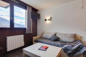 un salon avec un canapé et une table dans l'établissement Appartements avec balcon vue sur la montagne - Serre Chevalier Chantemerle, à Saint-Chaffrey
