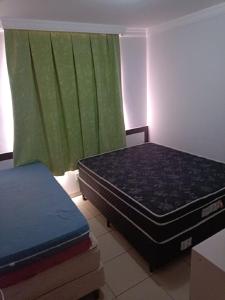 een kamer met 2 bedden en een groen gordijn bij Apart Flat Aguas da Serra in Rio Quente